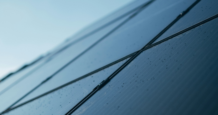Eine Solaranlage von schräg unten, darauf leichte Regentropfen, ein kleines Stück grauer Himmel oben links